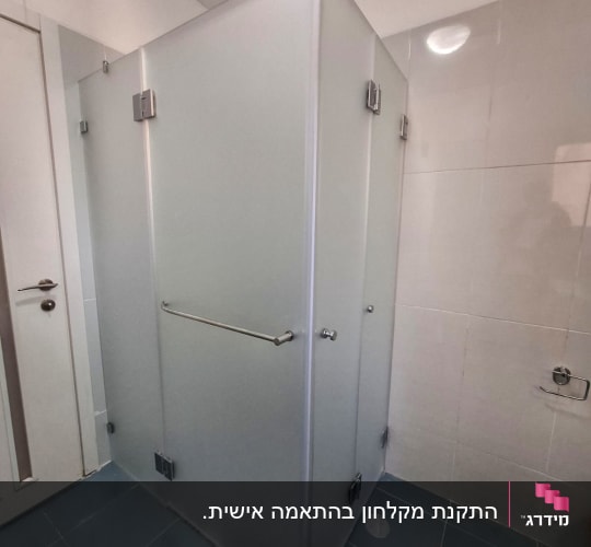 מקלחון פינתי מזכוכית חלבית המותקן בחדר רחצה מרוצף